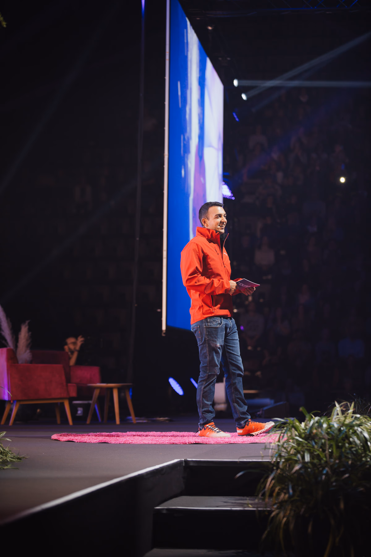 Redner in oranger Jacke auf der Bühne