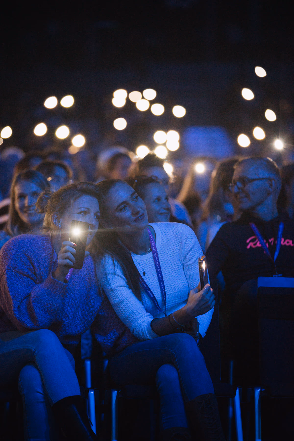Menge mit erhobenen Händen im blauen Bühnenlicht