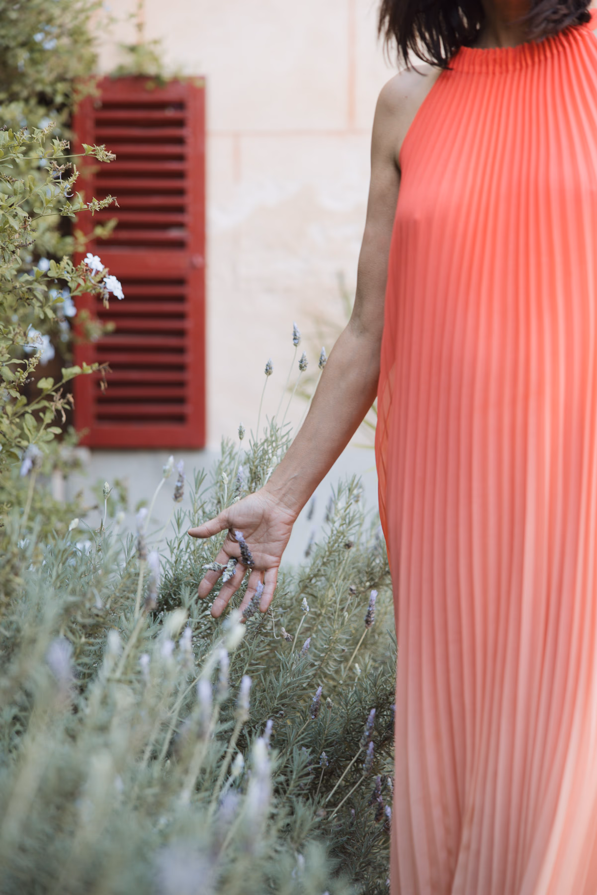 Orangefarbenes Faltenkleid vor lavendelfarbenem Gartenbeet