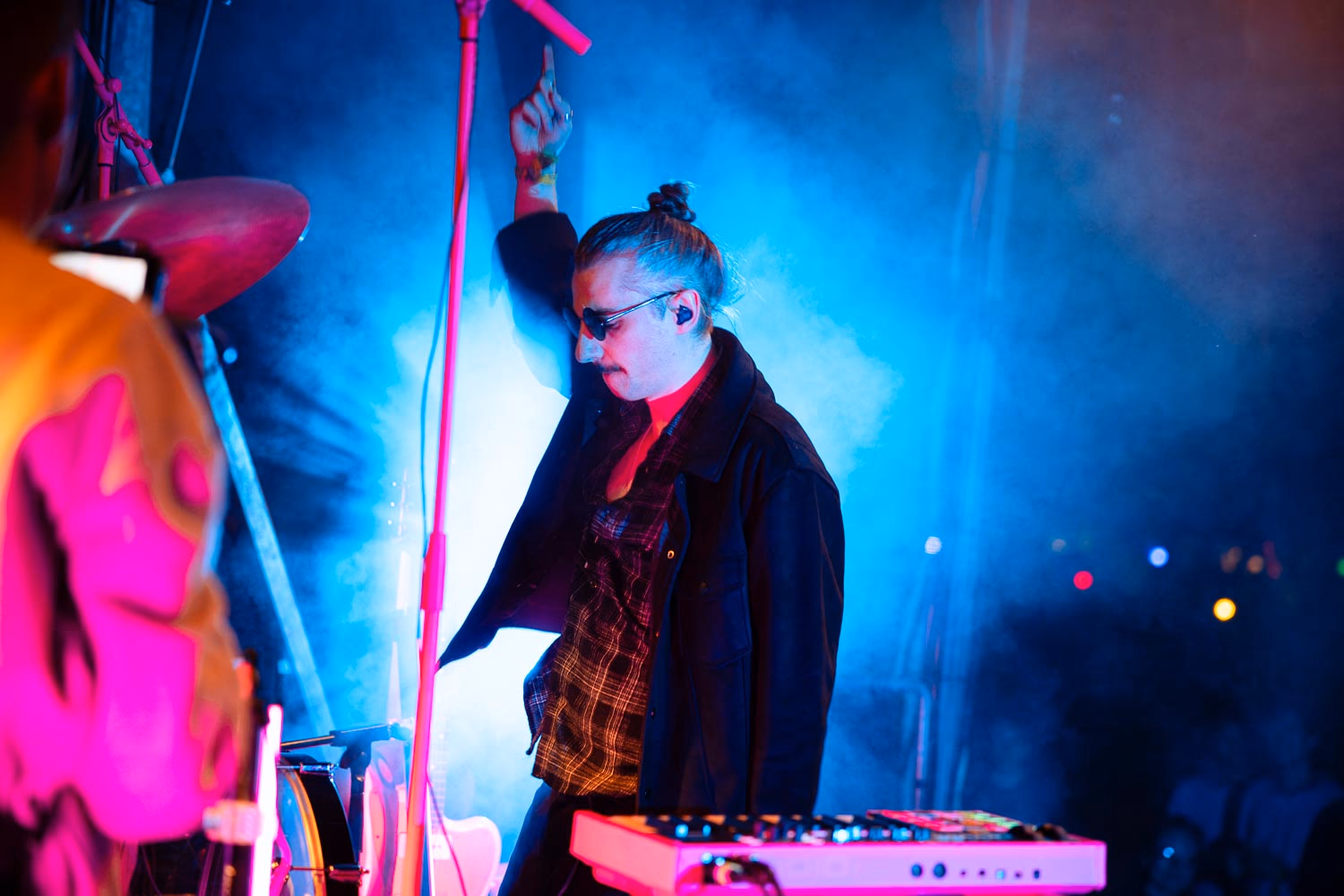 DJ mit Sonnenbrille zeigt in den Nebel der Bühne