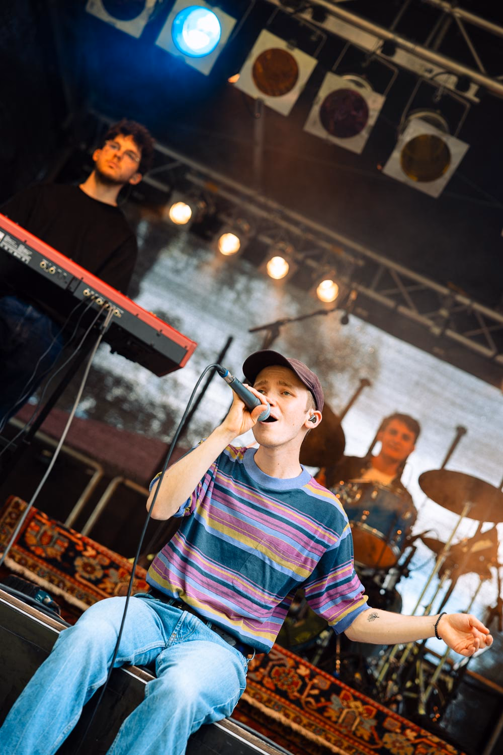 Sänger mit Cap performt sitzend vor der Band