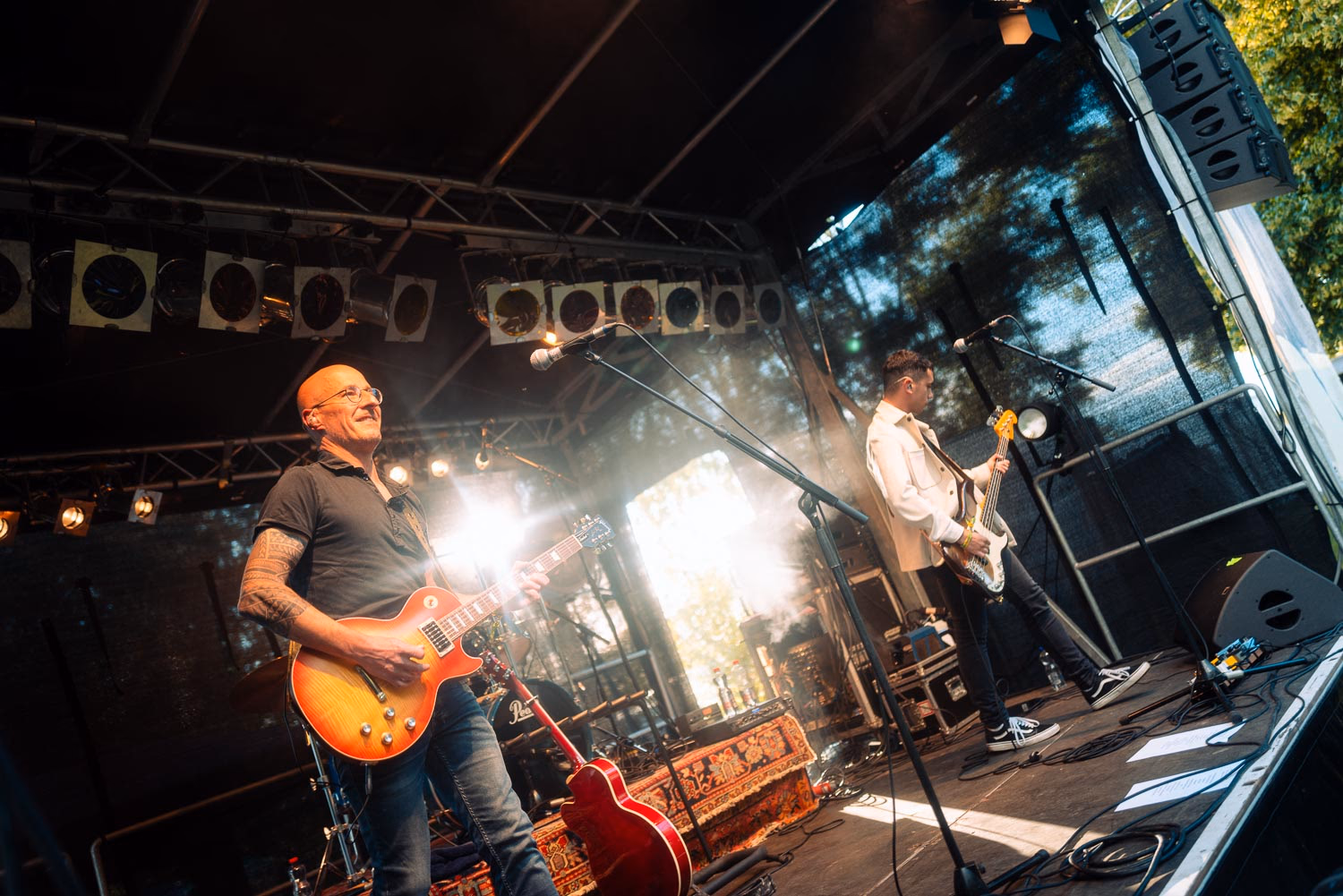 Gitarrist lächelt im Gegenlicht auf der Open-Air-Bühne